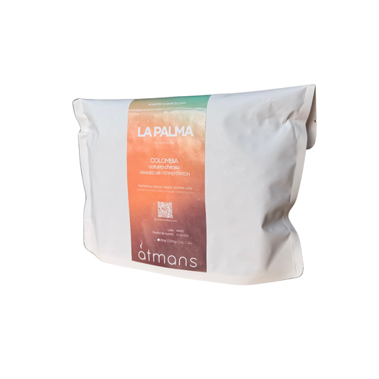 A white paper pouch of étans La Palma Colombia coffee, featuring a vertical label with a green-to-orange gradient and white text, set against a plain white background.